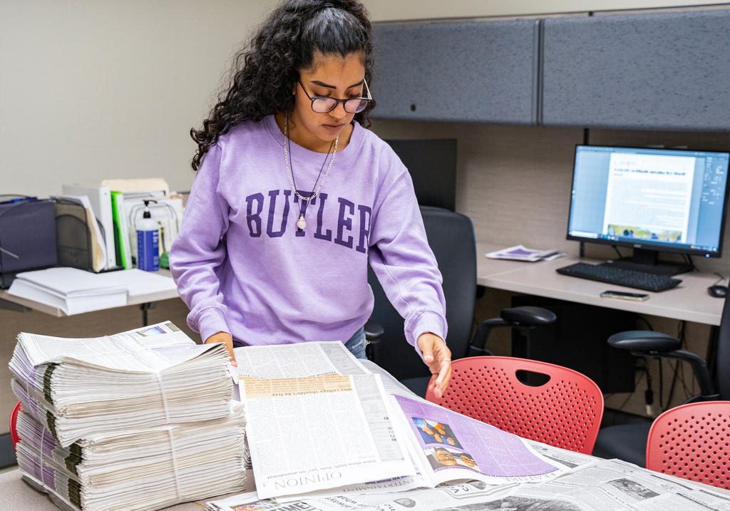 Journalism student sorting through printed newspapers